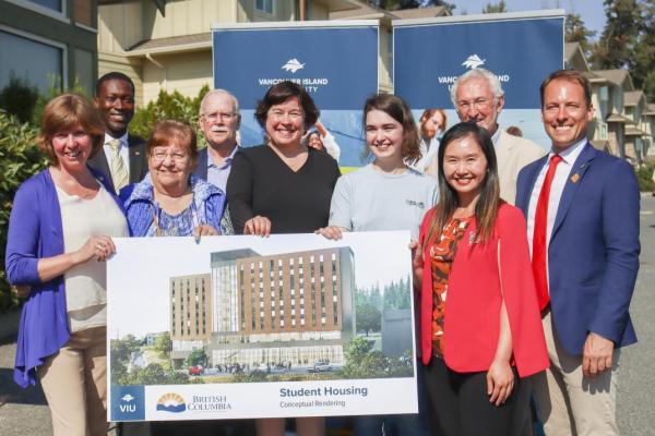 Group holds up a conceptual rendering of the new student housing facility coming to VIU's Nanaimo campus