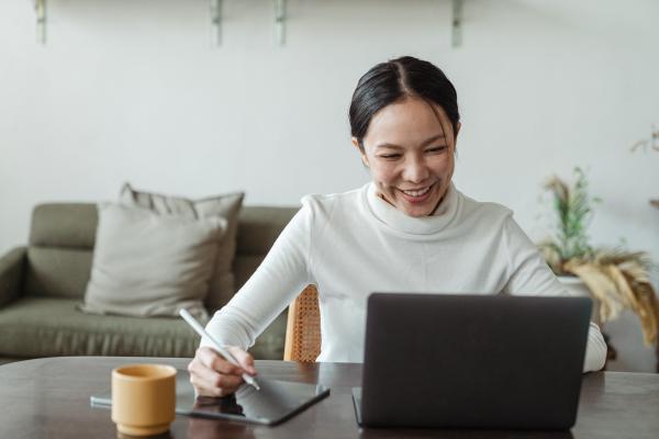 Women typing on a laptop with tablet next to her