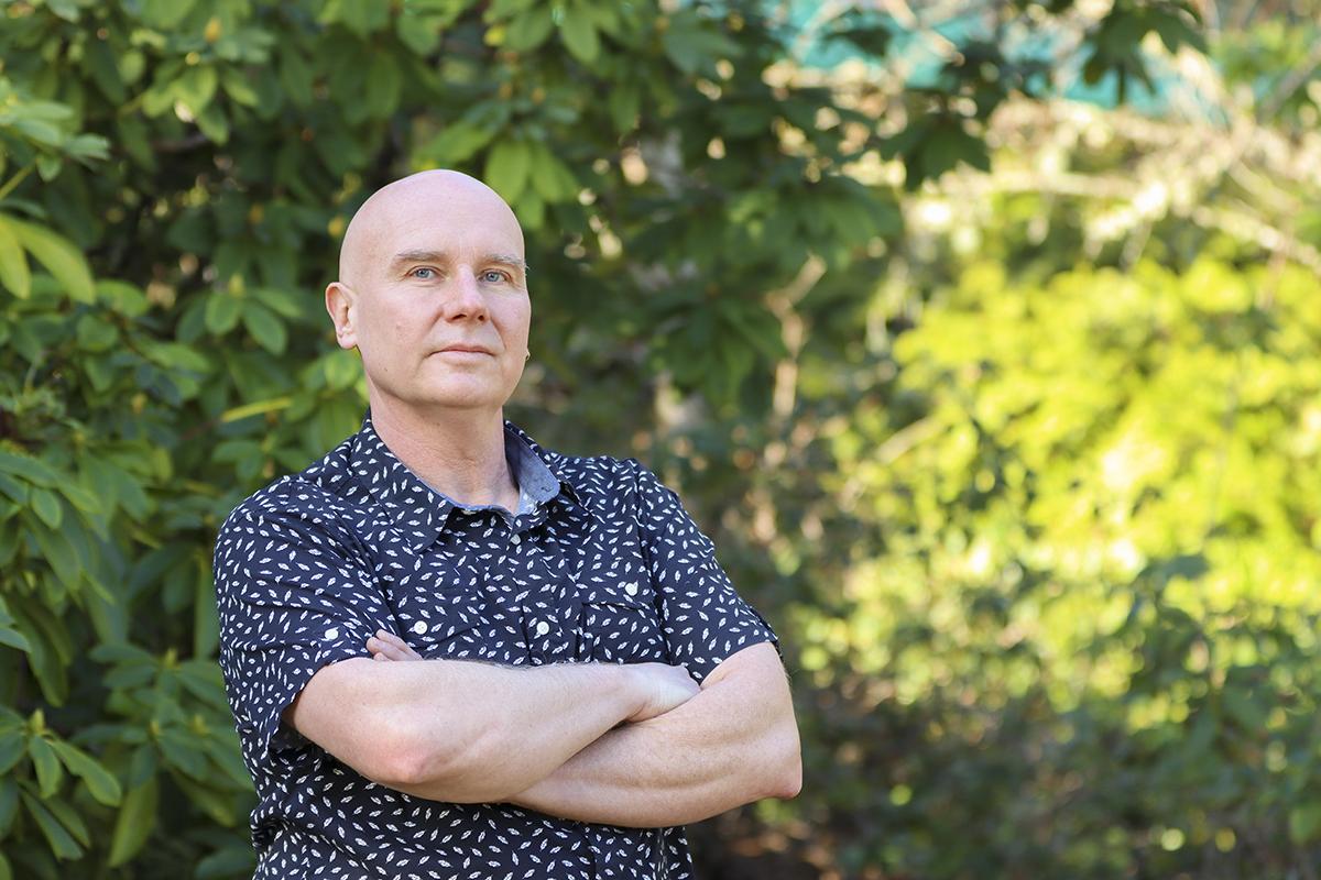 Dr. Chris Gill stands in a forested area at VIU's Nanaimo campus.