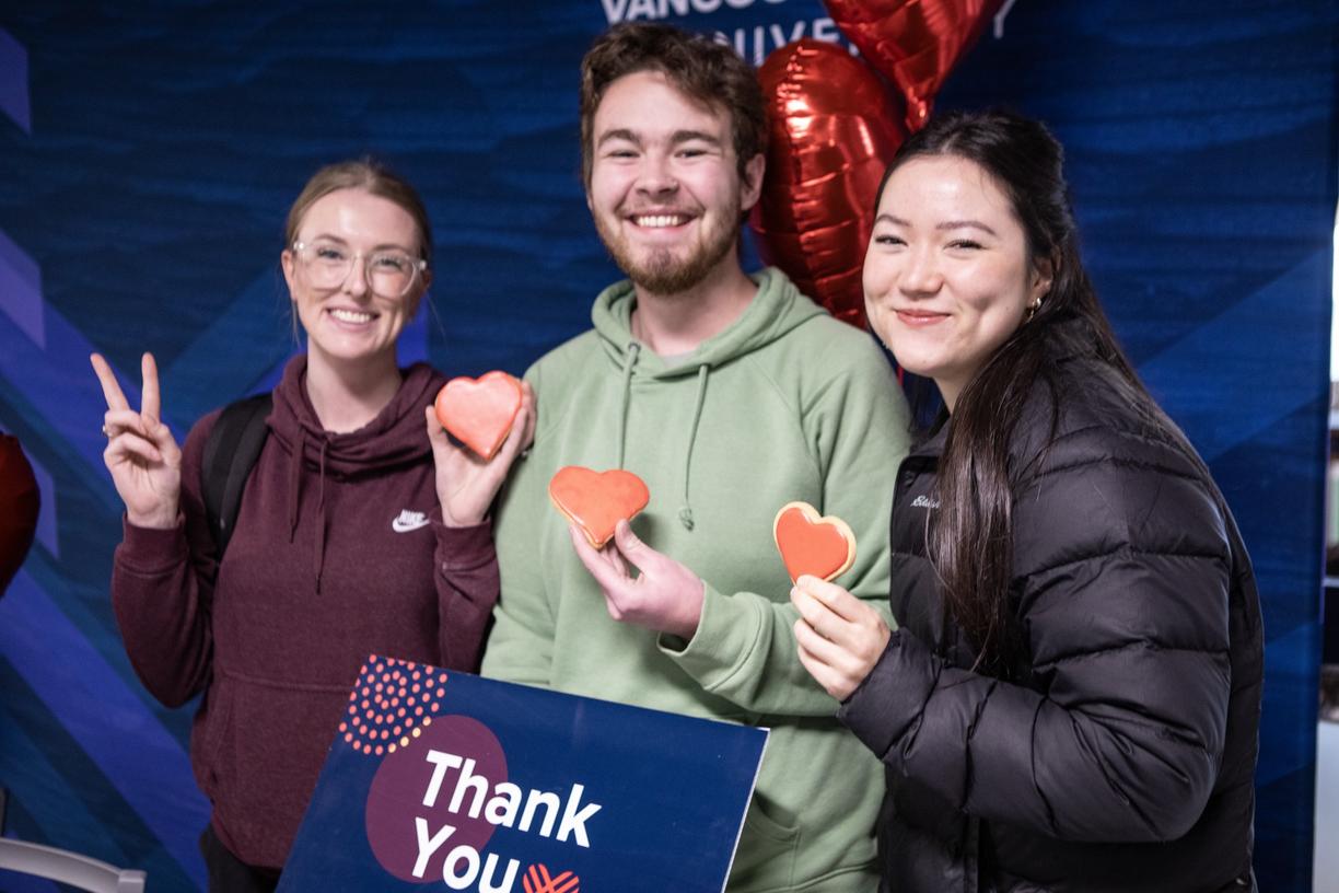 three students holding red heart cookies and a thank you sign