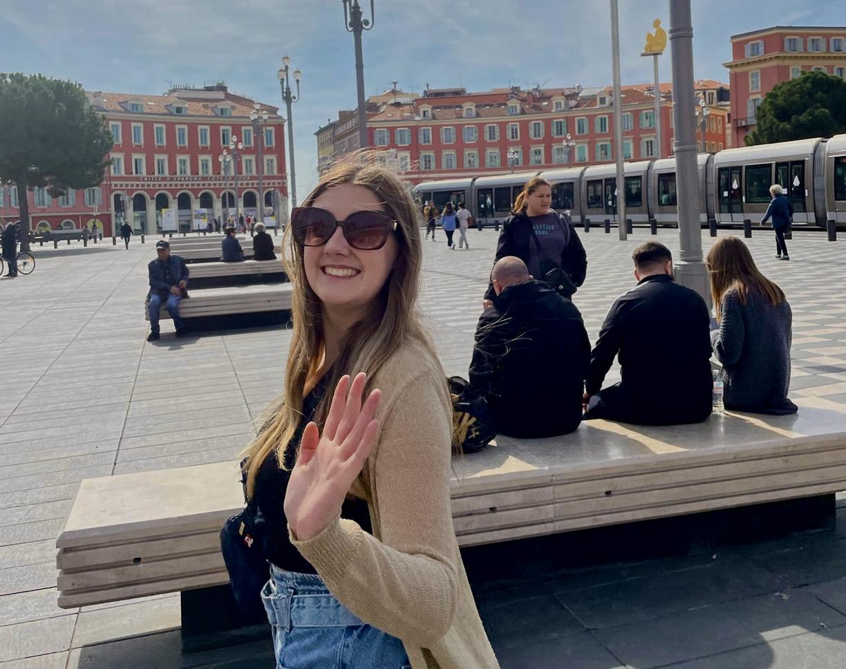 Jenna waves at the camera in a square