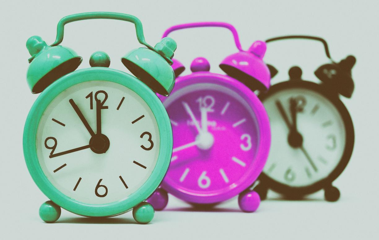 a picture of three small analog alarm clocks
