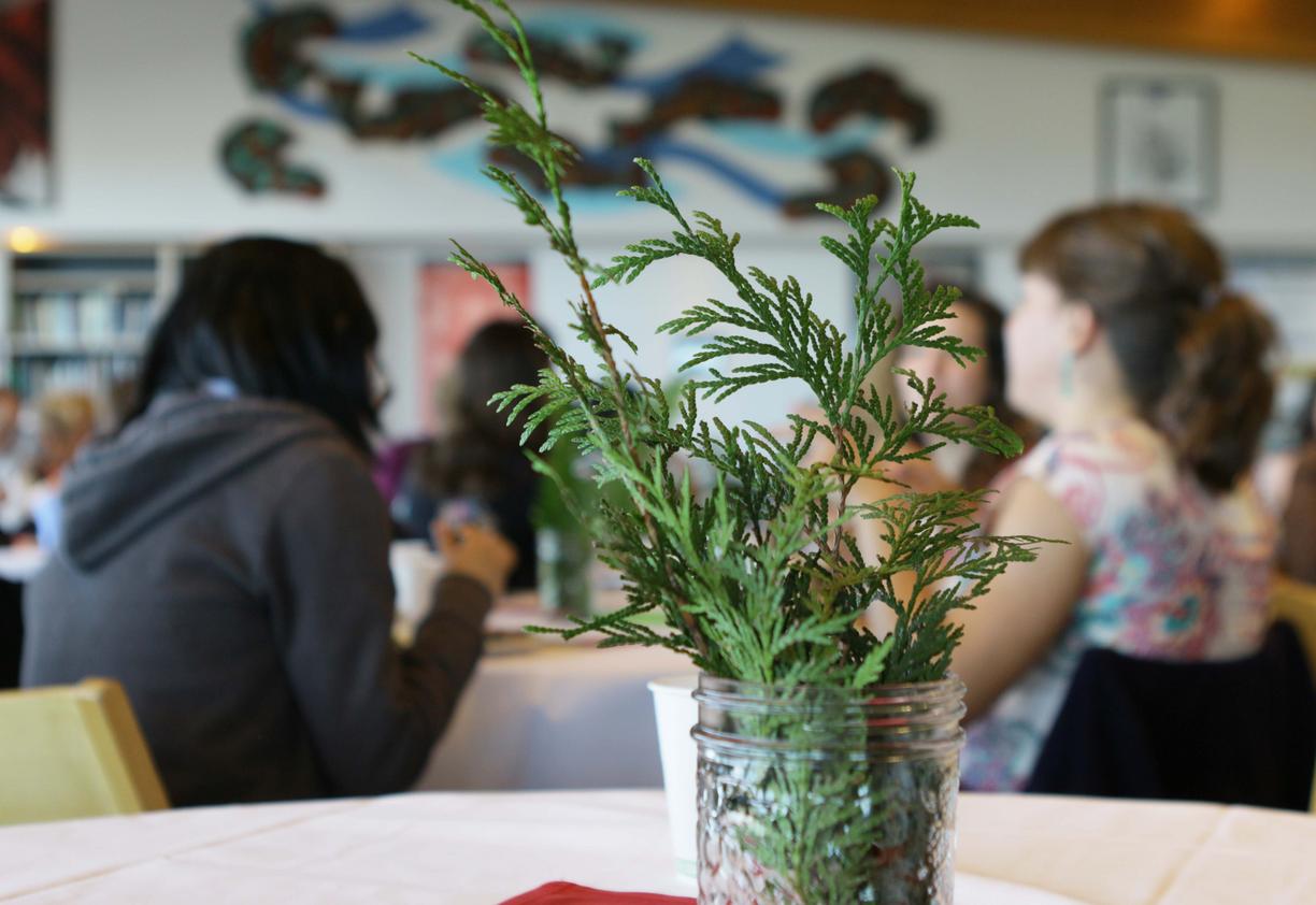 Cedar branch in a jar in foreground, people in VIU's Gathering Place in background