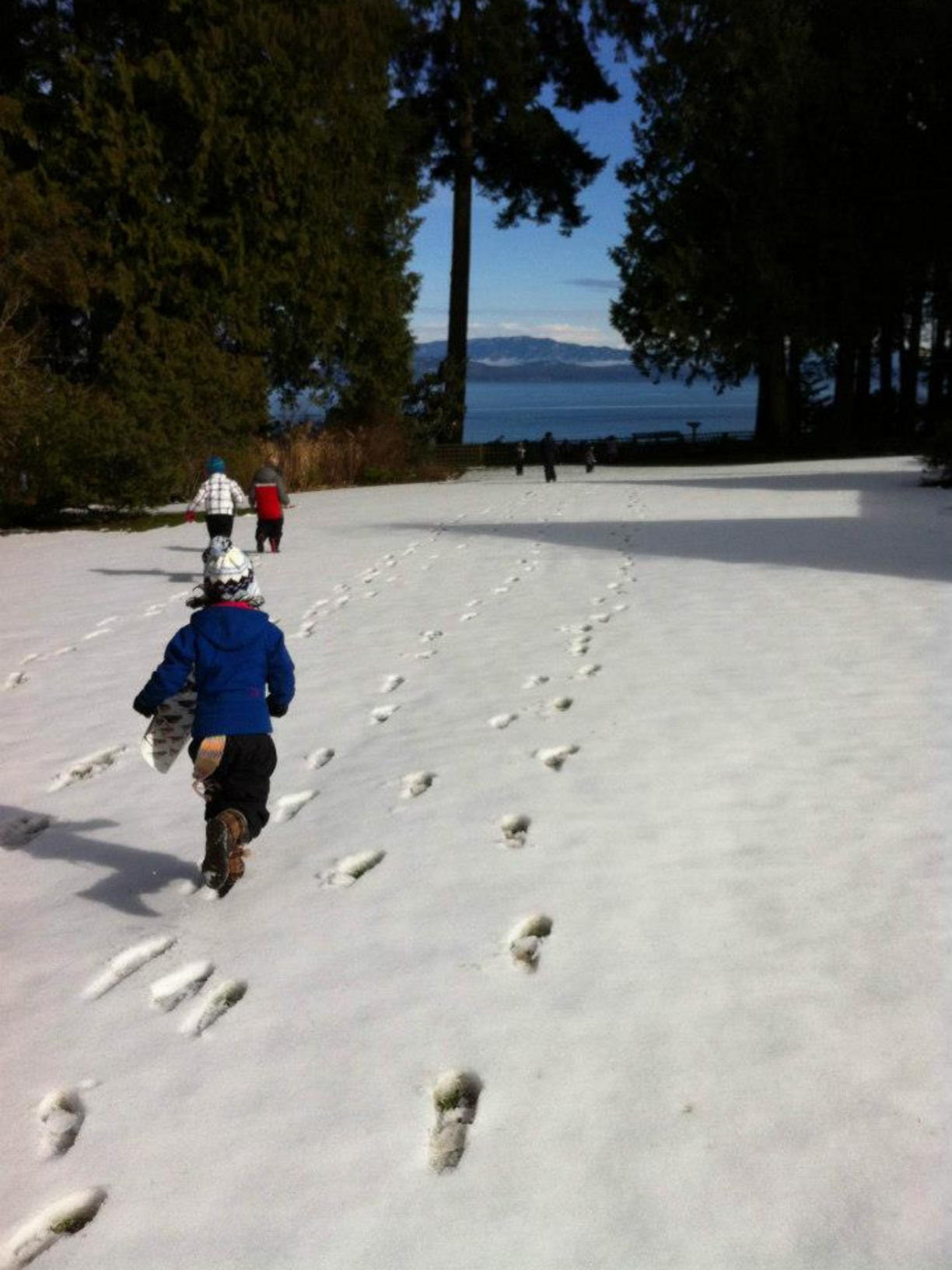 Children running across a snowy lawn