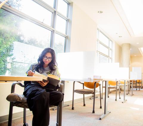 a student reads a textbook in the library