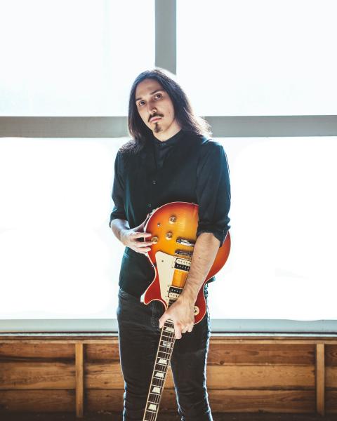 Portrait photo of Keanu holding a guitar