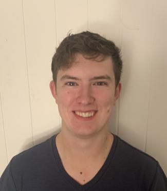 Evan Hessels, a VIU alum, stands in front of a white background smiling