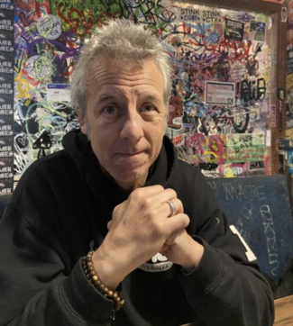 Justin McGrail with a graffiit wall behind him