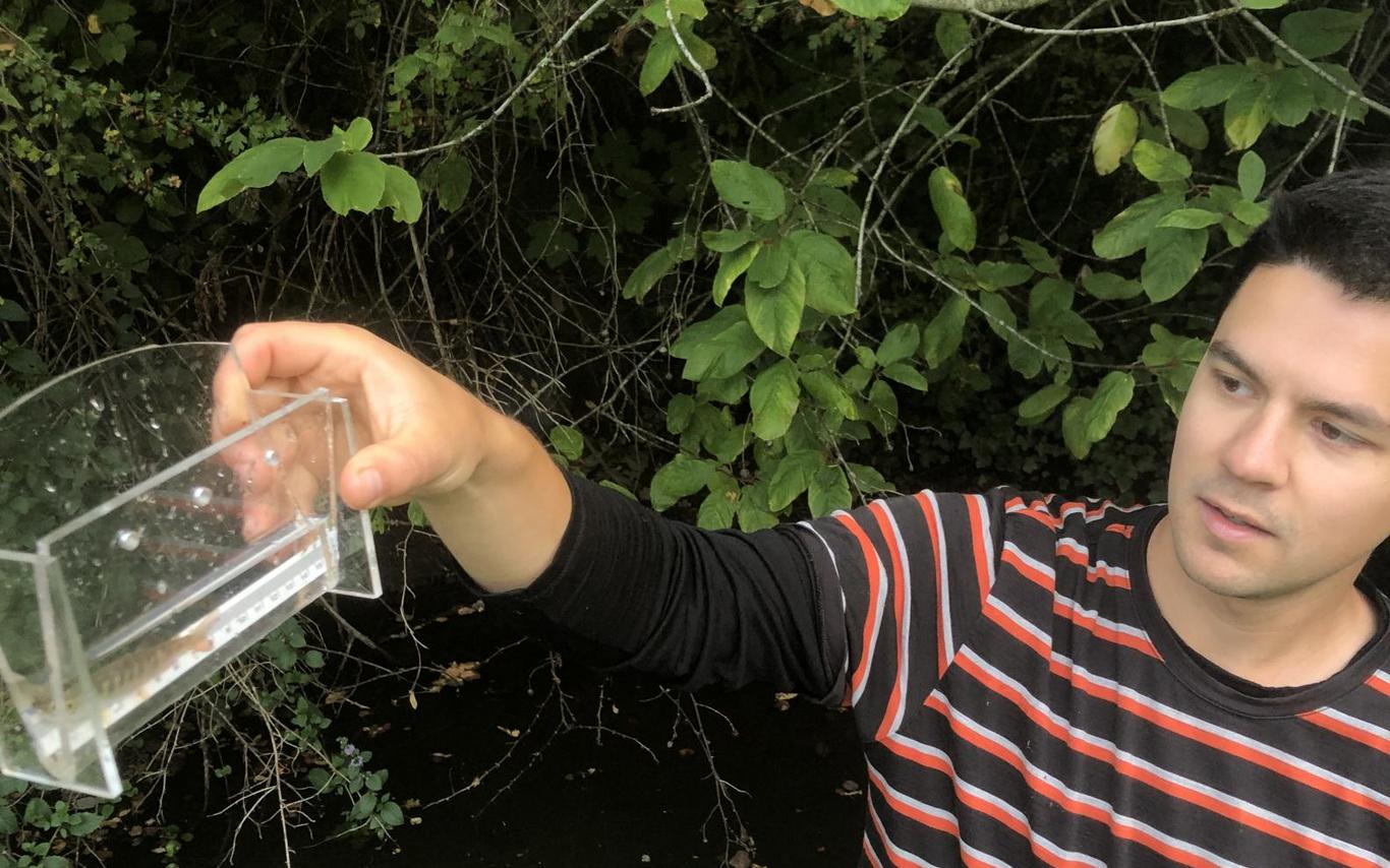 Joe Clark holds a container with a cutthroat trout fry.