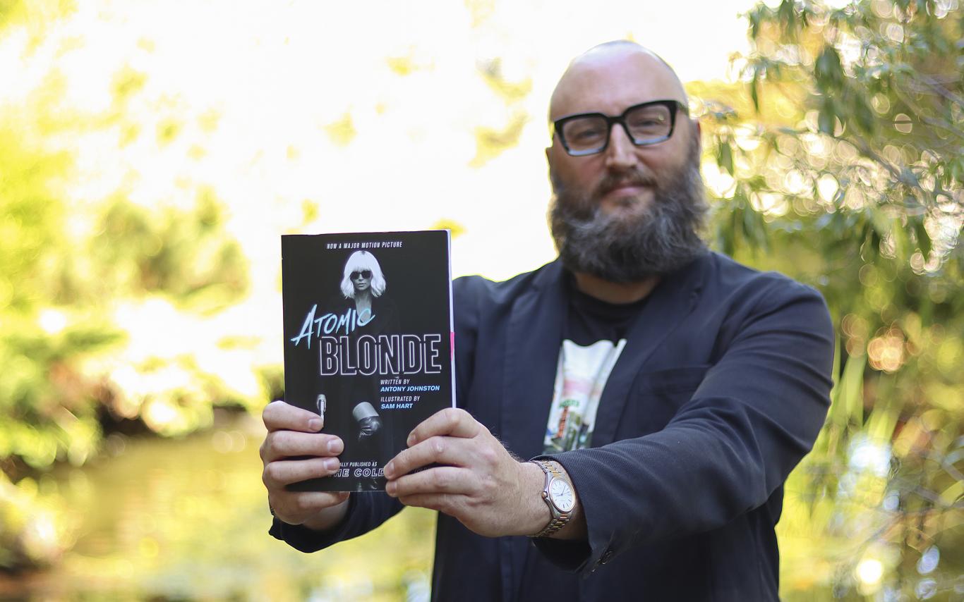 Theo Finigan holds out a copy of the book Atomic Blonde 
